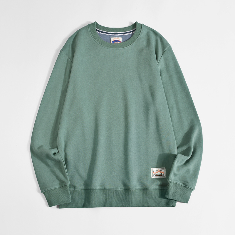 グリーンのクルーネック長袖Tシャツ、袖口ロゴパッチ付き