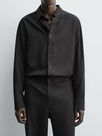 メンズ用黒のロングスリーブシャツを着用。前開きボタンとシンプルなシルエット。