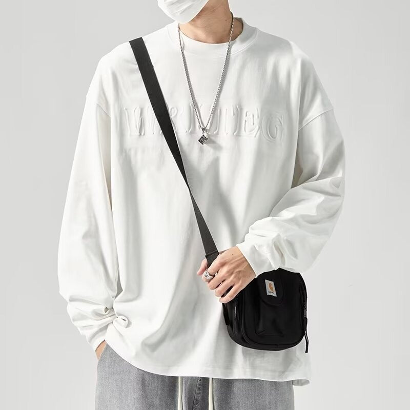 メンズ長袖Tシャツ。ゆったりした白のクルーネックで、胸元に同色の立体ロゴ入り